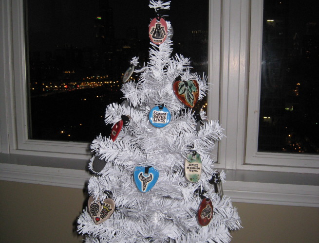 a small, white tabletop Christmas tree decorated with Surly-ramics